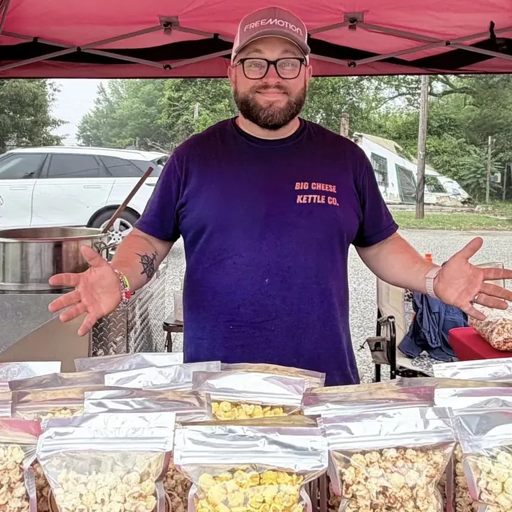 Josh at the Big Cheese Kettle Co. booth behind a table of fresh popcorn bags